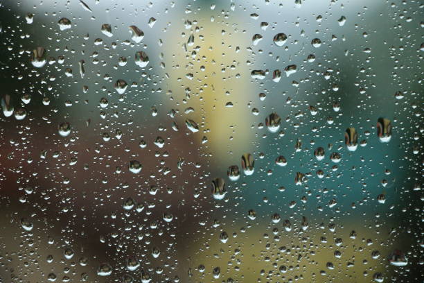 istock Rain drops on window with house and church in background 679555056