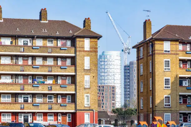 Council housing blocks contrasted with modern high-rise flats in the background in East London