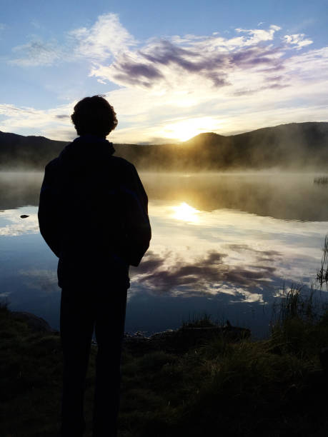 istock Young Man Contemplates Dawn Over Lake 679582608