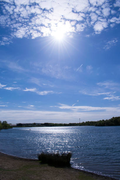istock Blue Sky Over Lake With Dramatic Clouds And Sun Beams 679582784