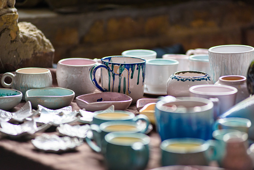A vibrant image of the blurred multi-colored ceramic mugs. Amazing antique decor. Ideas for handmade. Selective focus.