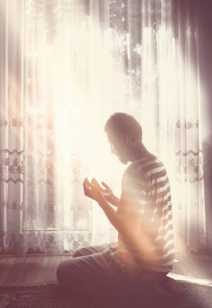 istock Muslim man praying indoor at dark room with bright window light source 679606454