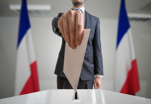 wybory we francji. wyborca trzyma kopertę w ręku nad piłką do głosowania. strzał szerokokątny. - lr pan zdjęcia i obrazy z banku zdjęć