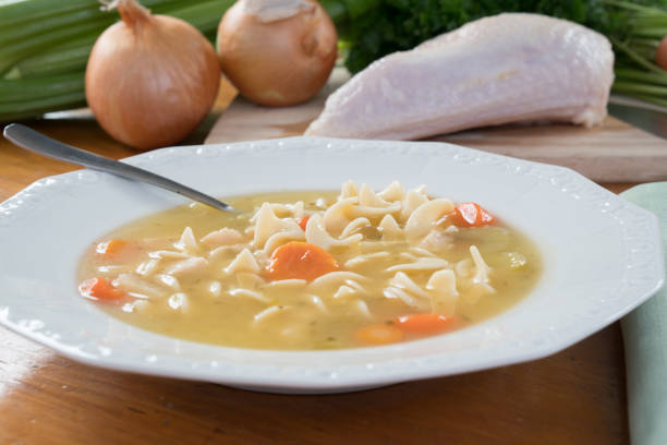 istock Bowl of Chicken Noodle Soup on a Table with Ingredients 679660764
