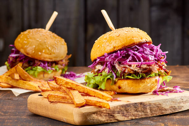 Two sandwiches with pulled pork, french fries and glass of beer on wooden background stock photo