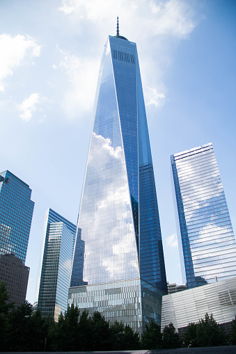 One World Trade Center and buildings reflect cloudy blue sky, New York