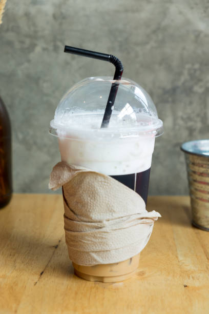 istock Iced coffee with straw in plastic cup on wood table 679693760