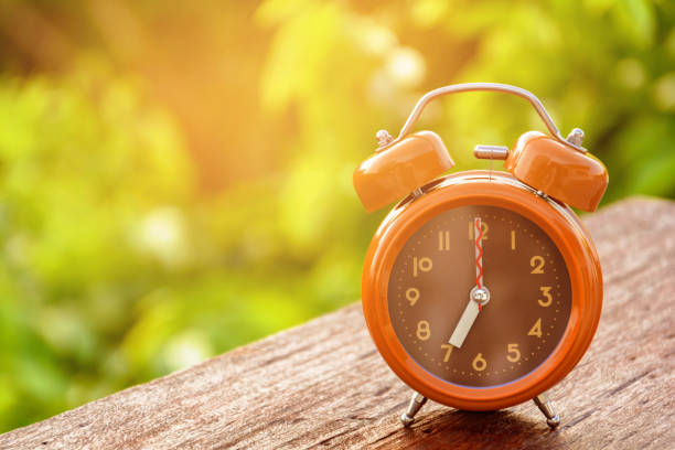 istock Brown clock on an old wood table 679694088