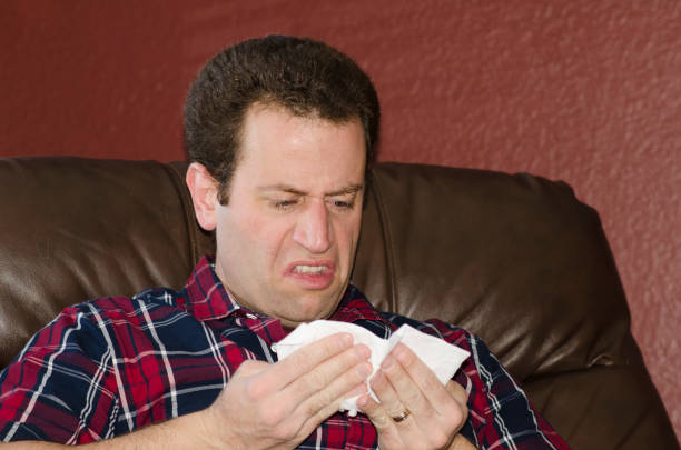 istock Sick man looking at a tissue after blowing his nose. 679710800