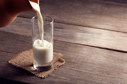 jug of milk with an old country table, a white drink is poured into a glass