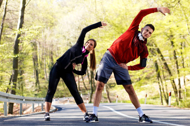 istock Young man and woman stretching muscles on the road before running. 679727250