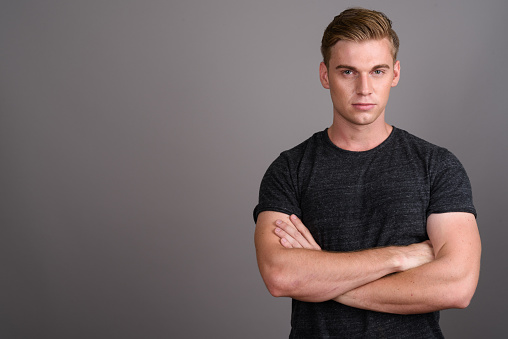 Studio shot of young muscular handsome man against gray background horizontal shot