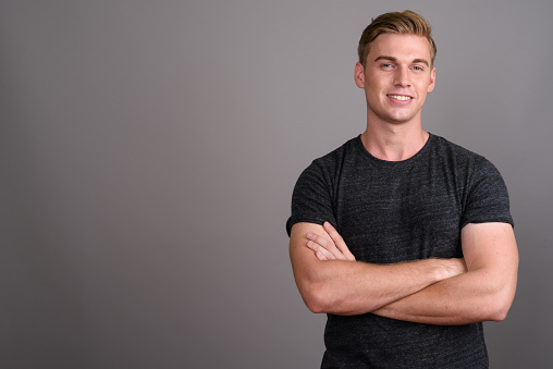 Studio shot of young muscular handsome man against gray background horizontal shot