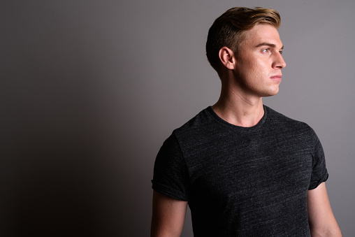 Studio shot of young muscular handsome man against gray background horizontal shot