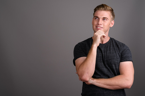 Studio shot of young muscular handsome man against gray background horizontal shot