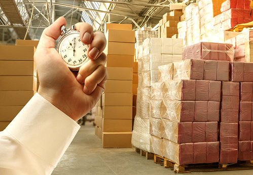 Paper products storehouse and stopwatch in male hand