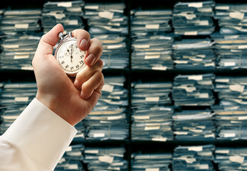 Paper documents stacked archive and stopwatch in male hand
