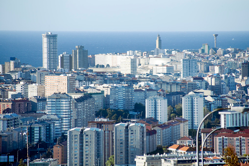 A Coruña cityscape, Torre de Hercules and sea horizon background. Tall residential buildings in the foreground.