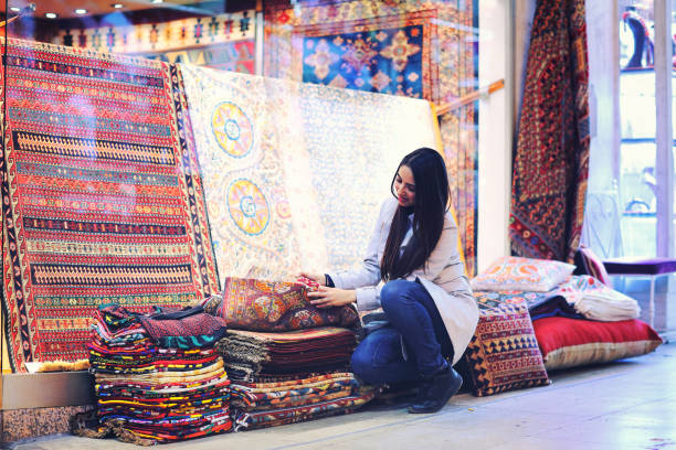 schöne junge frau kaufen teppiche im großen basar, istanbul, türkei - bedding merchandise market textile stock-fotos und bilder