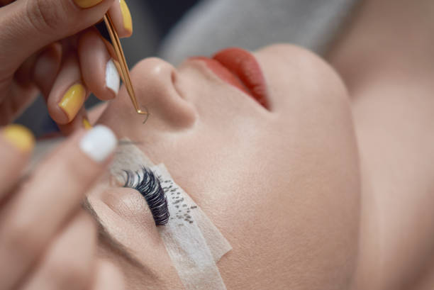 beauty treatment, applying false eyelashes beautician hands with working tools applying false eyelashes to her customer in spa salon, beauty treatment concept. false lashes stock pictures, royalty-free photos & images