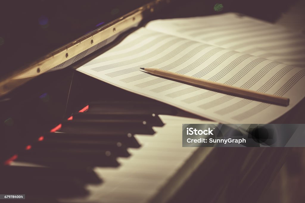 Compose Concept. Pencil and sheet music on the piano keyboard Music Stock Photo