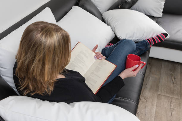 istock Rear and from a larger angle view of young woman reading a book 679814352