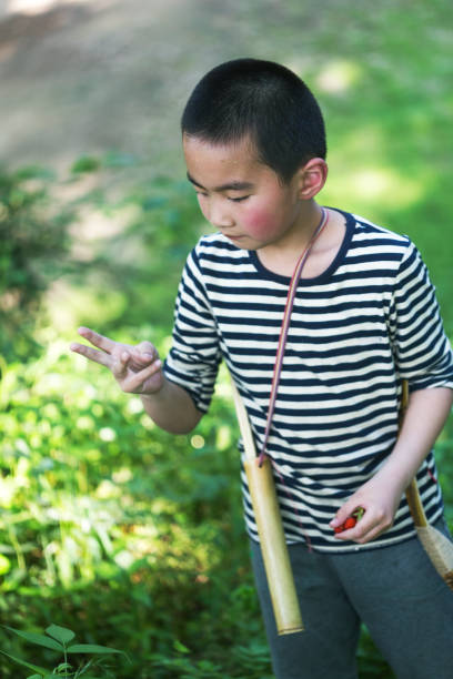 istock asian boy with bow and arrow in the forest 679819148
