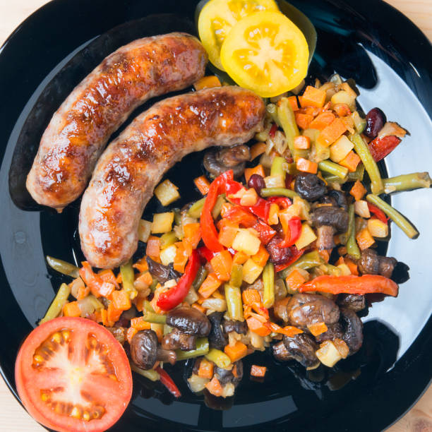 istock Fried sausages with vegetables on a kitchen table with tomatoes 679819778