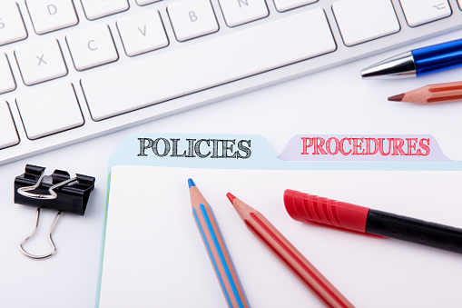 Policies and Procedures. Folder Register on a white Office Table
