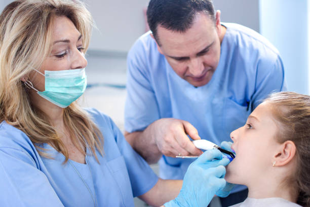 istock Dentists examining girl's teeth at dental office. 679829790