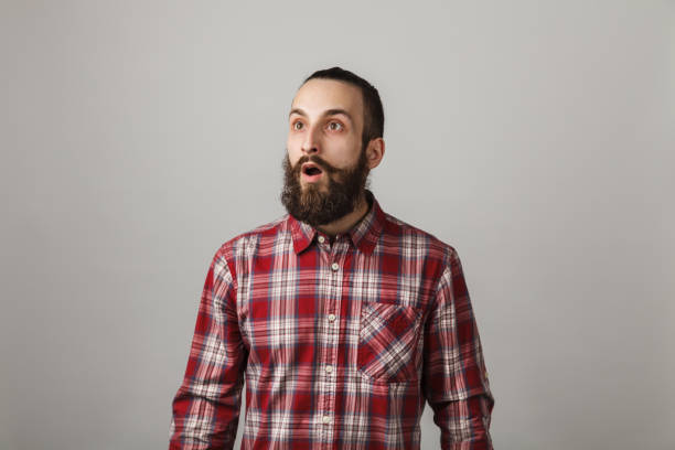 istock Bearded handsome man scares in red squared shirt on grey background 679839144