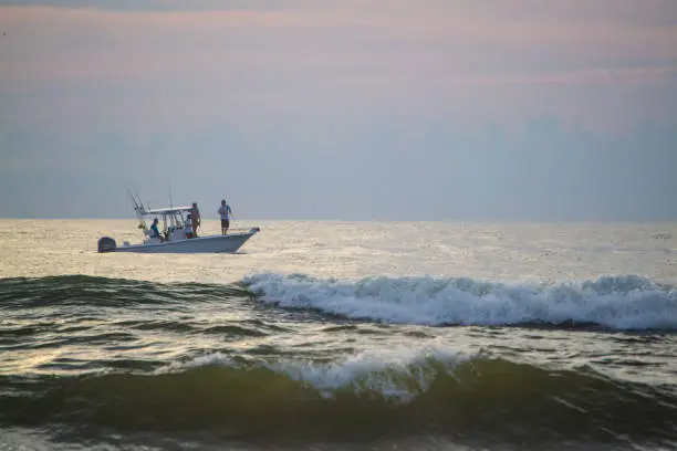 Men sport fishing just off the Florida coast at sunrise.