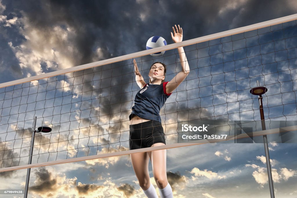 Female volleyball players jumping close-up Female volleyball player hitting the ball in the air on cloudy sky background Volleyball - Sport Stock Photo Female volleyball players jumping close-up Female volleyball player hitting the ball in the air on cloudy sky background Volleyball - Sport Stock Photo