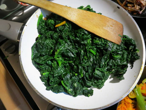 Homemade spinach on a Gas Stove in a pan. Homemade spinach in a home kitchen on a Gas Stove. spinach stock pictures, royalty-free photos & images