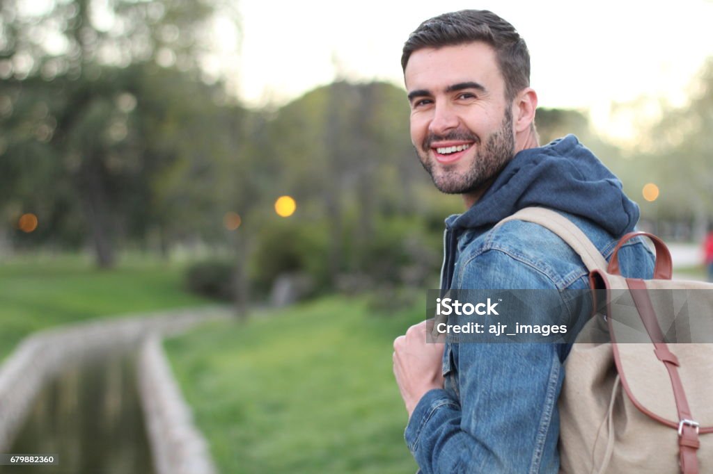 Smiley male holding backpack outdoors with copyspace Smiley male holding backpack outdoors with copy space. Men Stock Photo