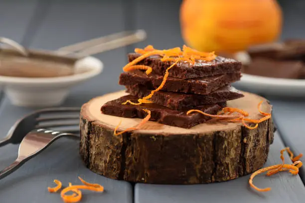 Craft chocolate bars decorated with orange peels on wood slabs closeup