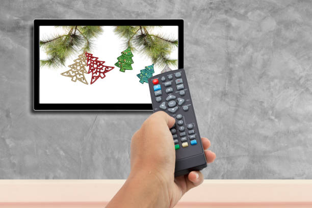 istock christmas decoration with hand holding remote control at television screen 679894594