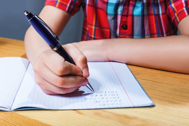 istock Pupil at the desk writing in notebook closeup view 679894978