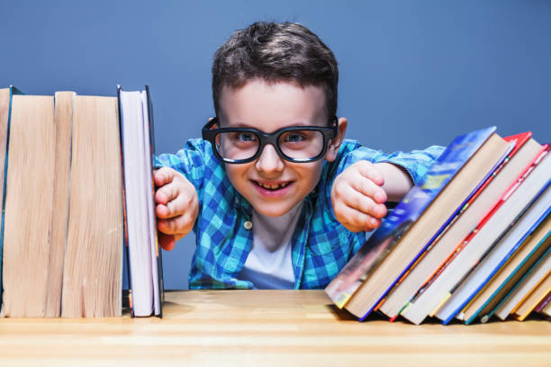 istock Happy pupil in glasses against books 679895634