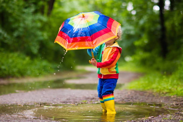 niño jugando en la lluvia bajo paraguas - 11981 fotografías e imágenes de stock