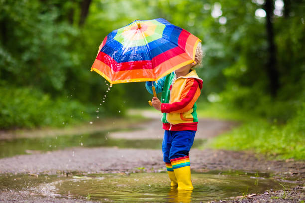 istock Child playing in the rain under umbrella 679895980