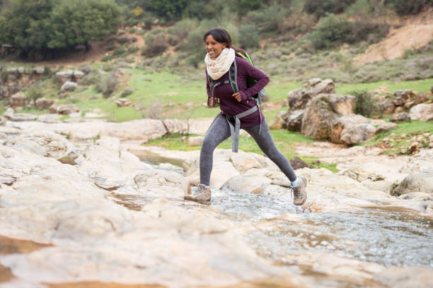 istock Hiker woman outdoors walking crossing river creek. 679896232