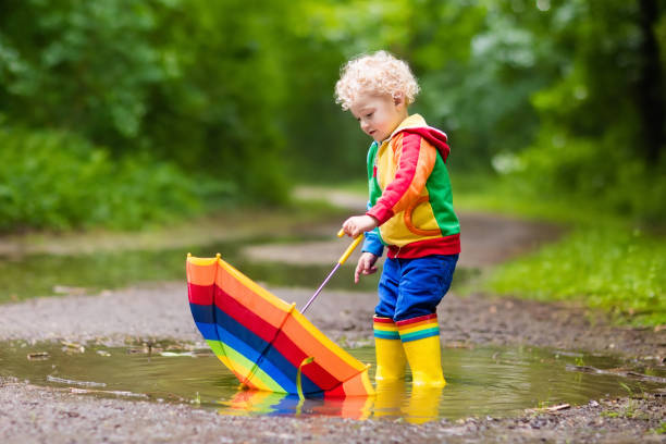istock Child playing in the rain under umbrella 679896770
