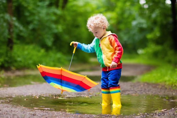 istock Child playing in the rain under umbrella 679896982