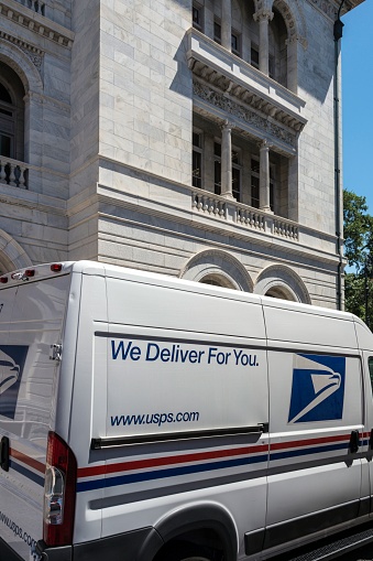 A vehicle of the United States Postal Service is parked in front of a post office in, Savannah, Georgia.