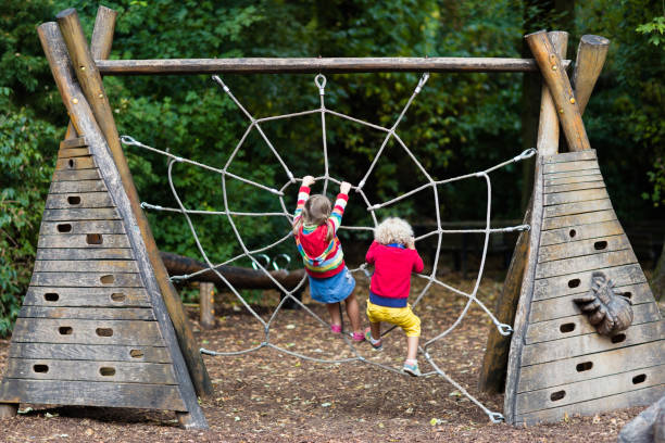Children climb on school yard playground Active children playing on climbing net at school yard playground. Kids play and climb outdoors on sunny summer day. Cute girl and boy on nest swing at preschool sport center. Family summer vacation. girl climbing ladder stock pictures, royalty-free photos & images