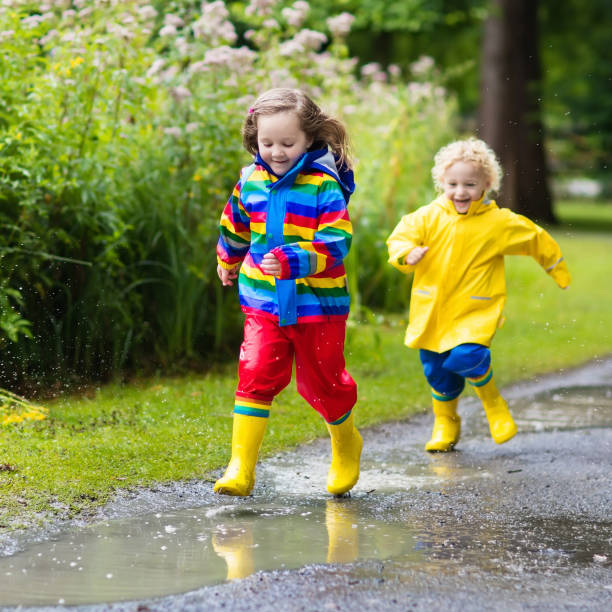 istock Kids play in rain and puddle in autumn 679916204