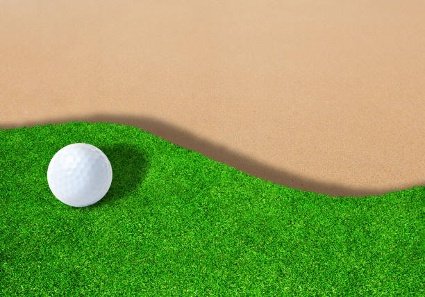 Golf ball on edge of sand trap bunker with copy space.