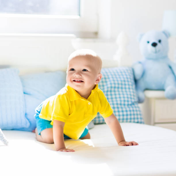istock Baby boy playing on bed in sunny nursery 679917056