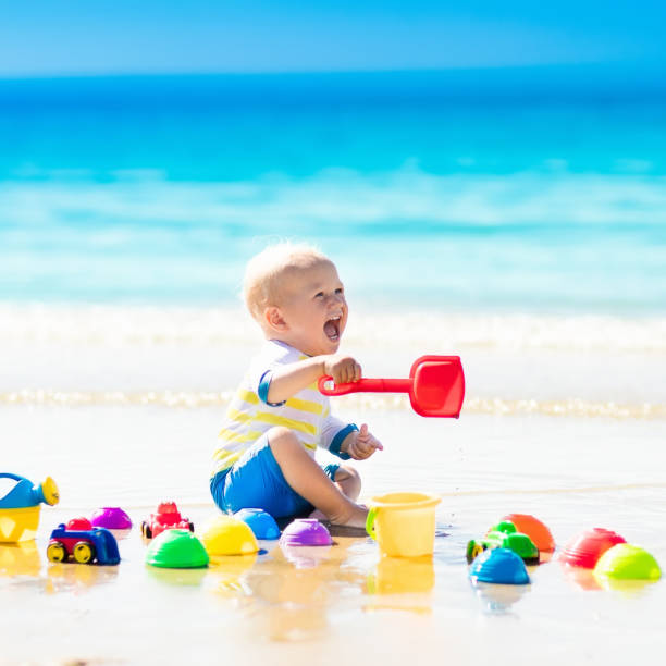 детские игры на тропическом пляже копать в песке - lifestyles child beach digging стоковые фото и изображения